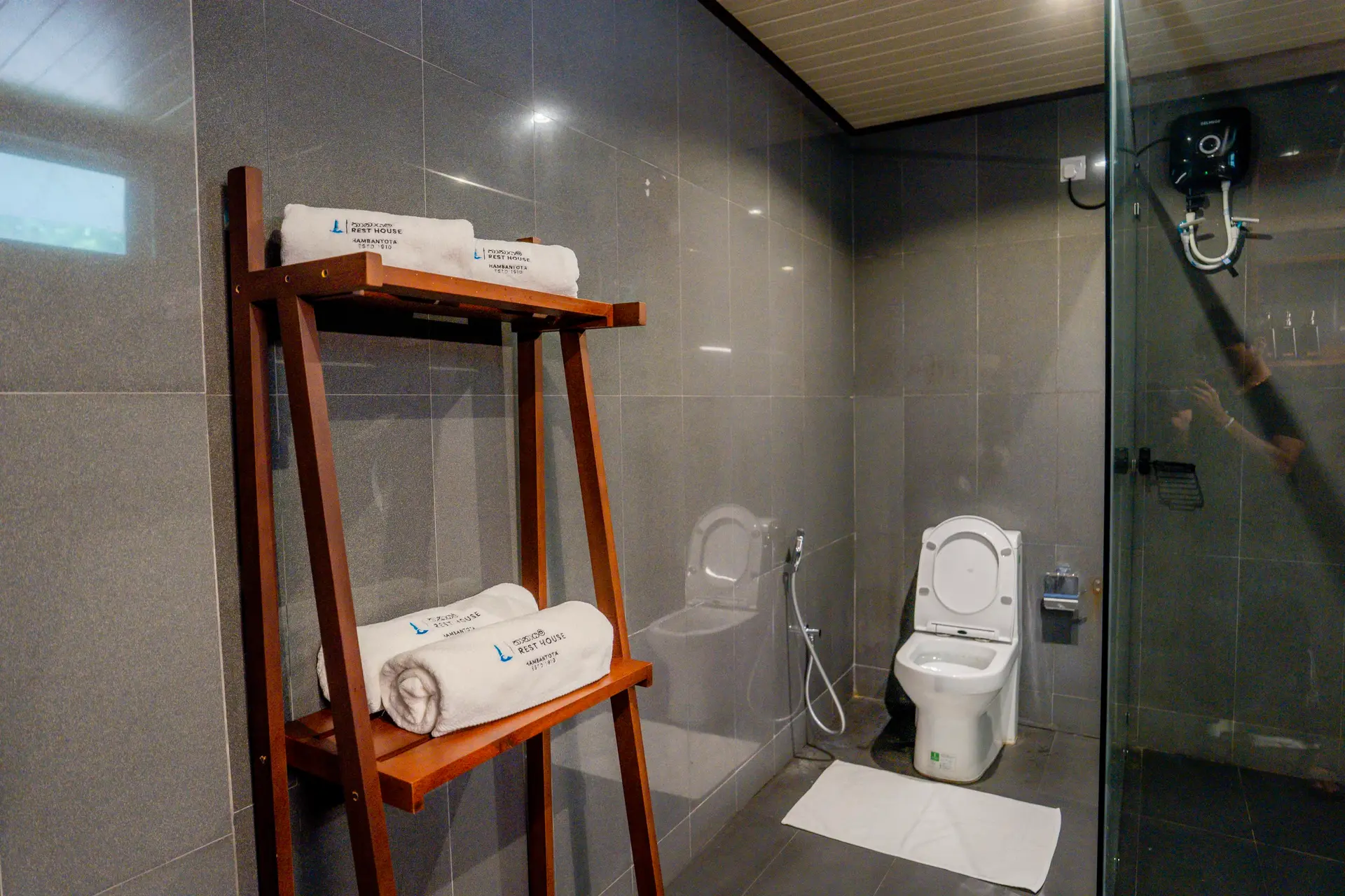 Rest House towels on a teak rack in the bathroom